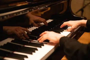 Duas mãos estão tocando em um piano.